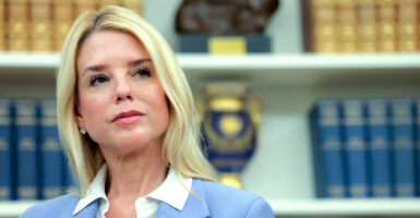 Attorney General Pam Bondi, with a backdrop of bookshelves with law books.