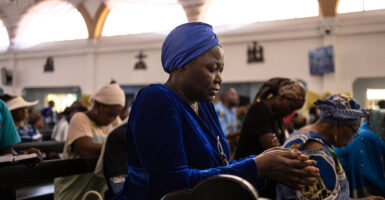 An African female worshipper—clad in all dark-blue attire, including a headdress—prays at Mass at the Church of the Assumption in Lagos, Nigeria, on April 21, following the death of Pope Francis.