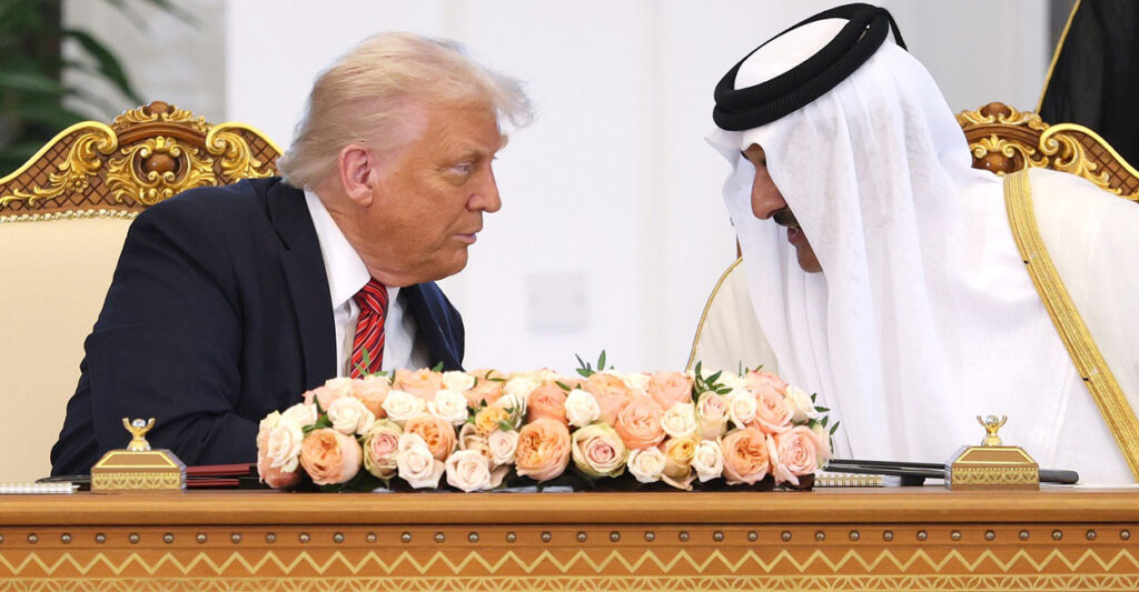 Donald Trump leans over and listens to Emir of Qatar Tamim bin Hamad al Thani as they sit at a table in Qatar.