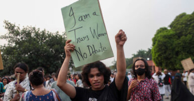 A person holds up a green sign that says, "I am a trans women. No debate."