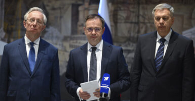 Three Russian officials stand in suits and talk to press after meeting with the Ukraine delegation.