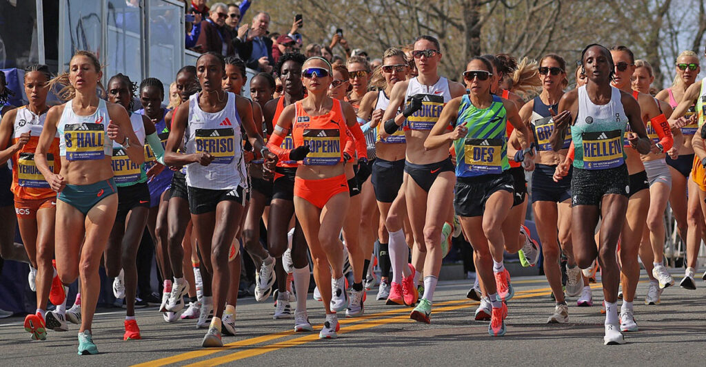 Participants in the Boston Marathon are grouped together and moving forward.