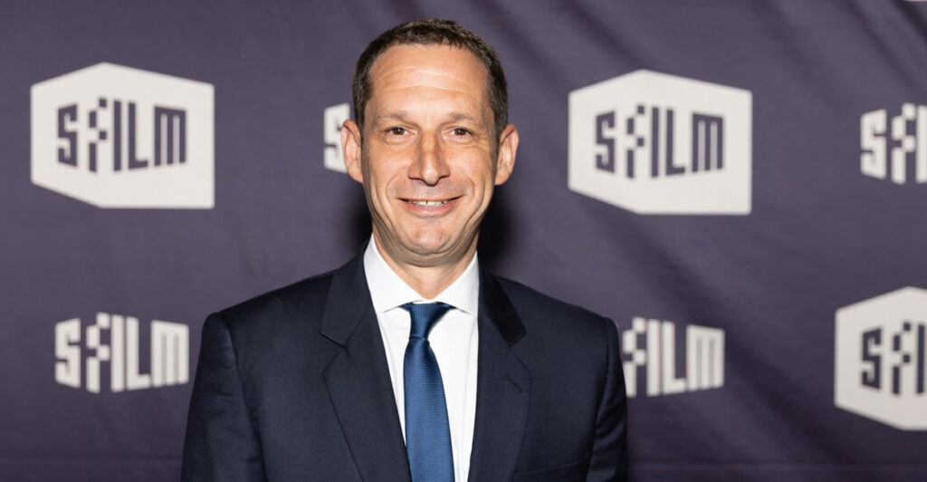 Daniel Lurie looks straight ahead and smiles as he poses for a photo at a film festival.