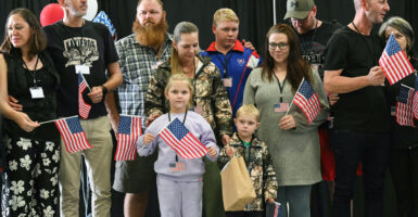 a group of white Afrikaners, including men, women, and children, wave small American flags as they arrive in the United States for asylum