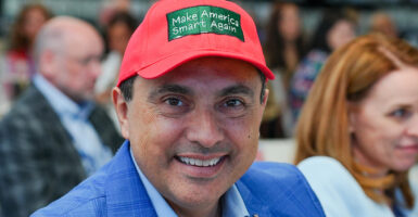 Alfredo Ortiz in a blue suit wears a Make America Smart Again hat