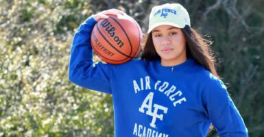 18-year-old Ava Moore in a blue Air Force sweatshirt, holding a basketball.