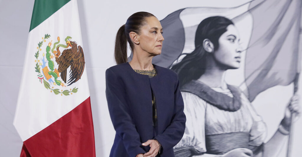 Claudia Sheinbaum in front of a Mexican flag