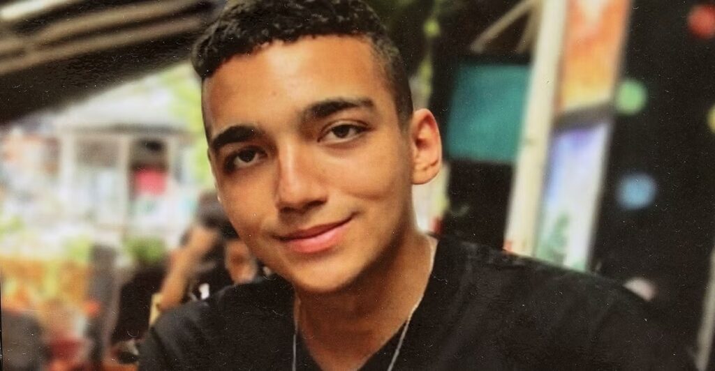 Edan Alexander looks at the camera on a black t-shirt.