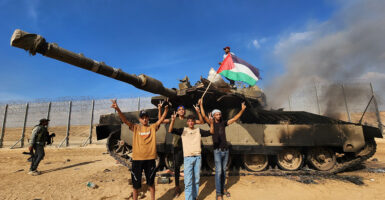 Hamas terrorists unfurl a Palestinian flag as they destroy an Israeli tank in Gaza City, Gaza, on Oct. 7, 2023.