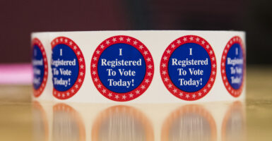 A roll of round stickers reading "I Registered to Vote" today rests on a reflective, polished table.