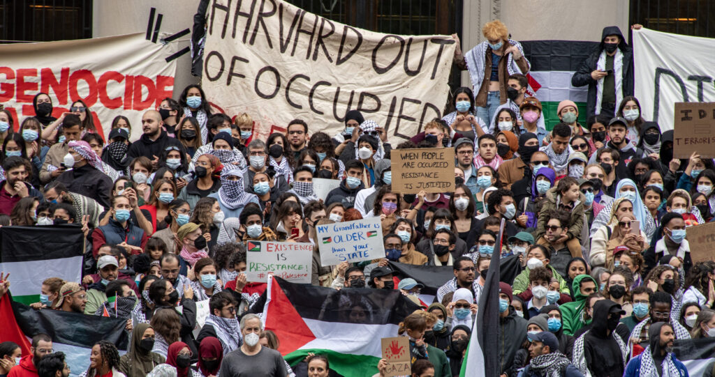 A large crowd of anti-Israel protesters gather at Harvard Yard, waving Palestinian flags and signs reading "Genocide in Gaza."