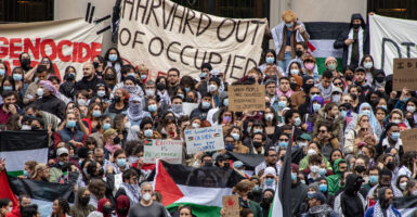 A large crowd of anti-Israel protesters gather at Harvard Yard, waving Palestinian flags and signs reading "Genocide in Gaza."
