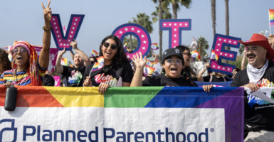 Three women and a male carry a Planned Parenthood banner ringed in rainbow colors during the Orange County Pride Parade in 2024.