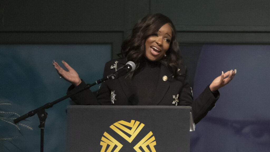 Jasmine Crockett behind a podium, arms spread wide.