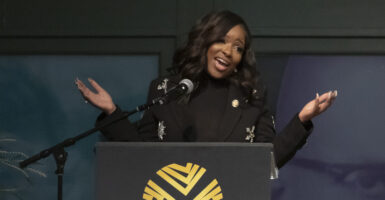 Jasmine Crockett behind a podium, arms spread wide.
