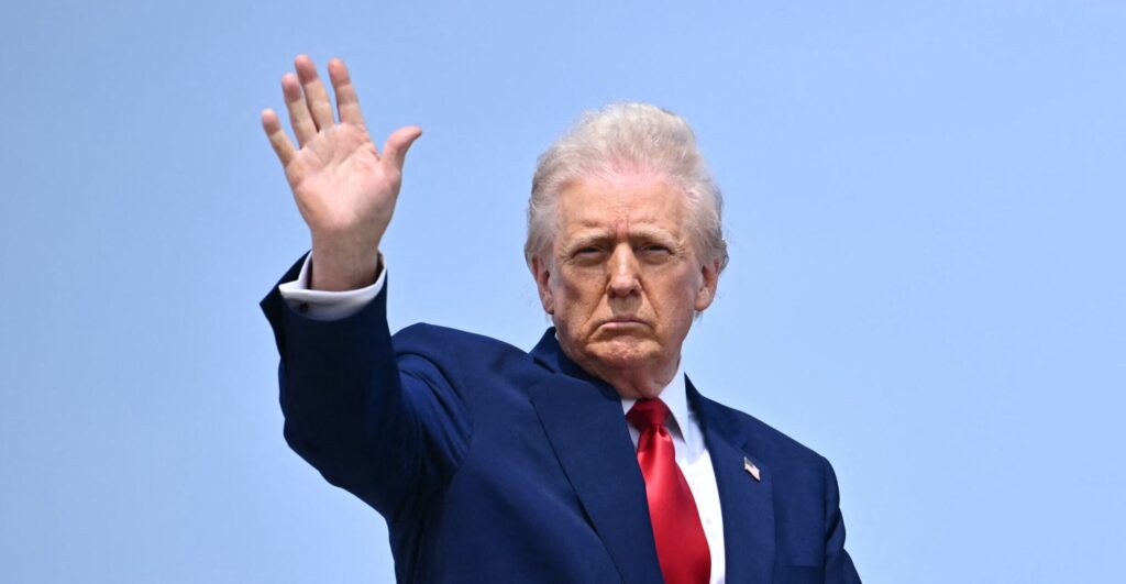 President Trump, against a clear blue sky, waves.