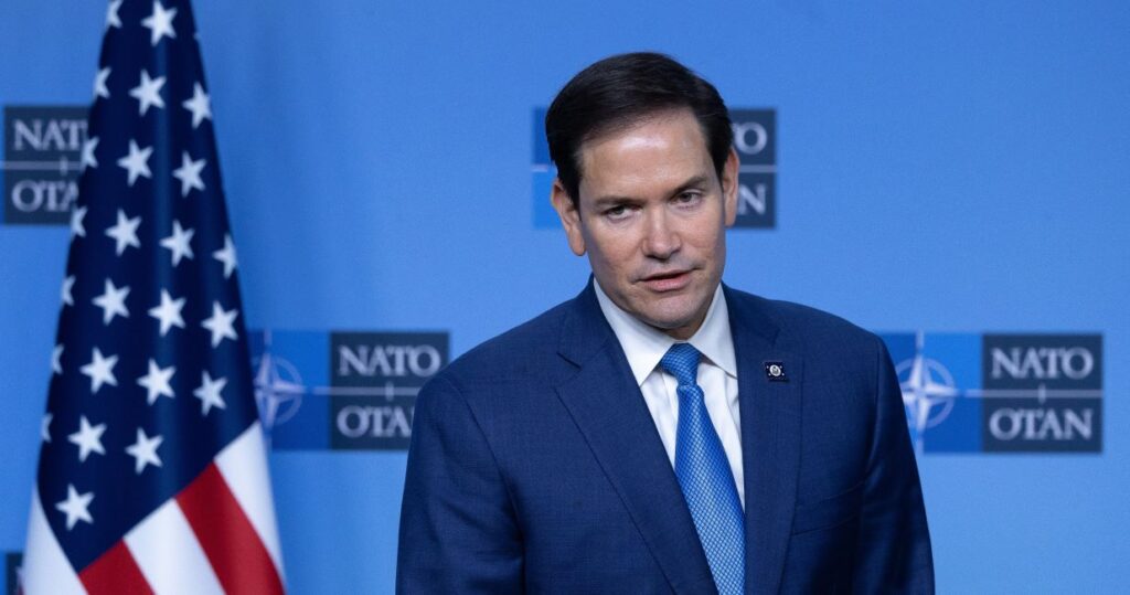 Secretary of State Marco Rubio speaks next to an American flag at April 3, 2025 NATO meeting.