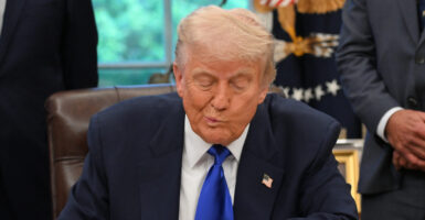 President Trump, his mouth humorously askew, looks down toward his desk.