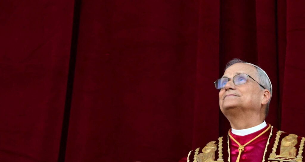 American-born Pope Leo XIV gazes toward heaven against a burgundy background.