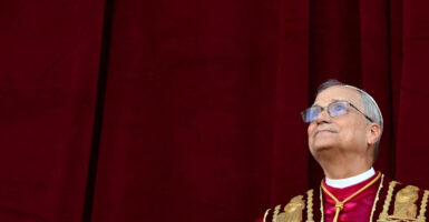 American-born Pope Leo XIV gazes toward heaven against a burgundy background.