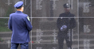 Riverhead, NY, Police Officer Bill Krause stands in front of the black wall etched with the names of New York officers who have lost their lives. Officer Krause's reflection is seen in the wall.