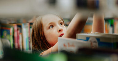 A young girl looks at a book with wide eyes in a library