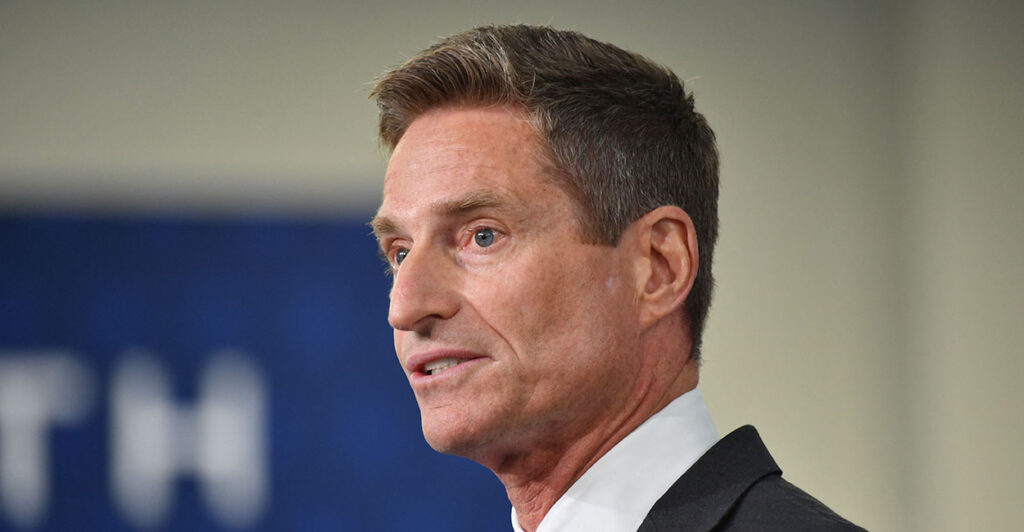 Lockheed Martin CEO Jim Taiclet in a suit with a blue and tan background