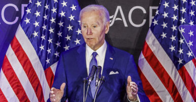 Joe Biden in a blue suit in front of American flags
