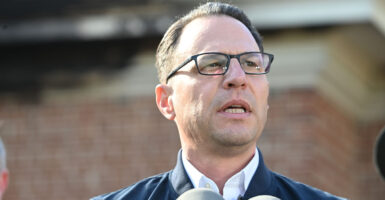 Josh Shapiro in a suit in front of a brick building.