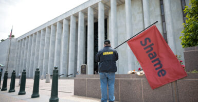 A man holds a red flag that reads "Shame" outside the Library of Congress on May 12 in Washington, D.C. Days earlier, President Donald Trump had fired Carla Hayden as the head of the Library of Congress.