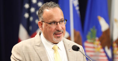 Miguel Cardona in a checkered suit with a yellow tie