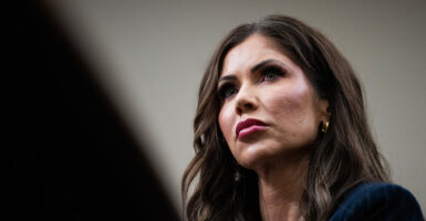 Homeland Security Secretary Noem looks ahead in a navy blazer while seated during a hearing.