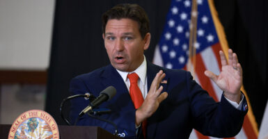 Florida Gov. Ron DeSantis in a blue suit with a red tie and an American flag pin