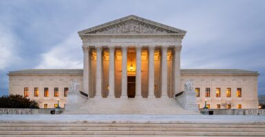 The United States Supreme Court building is lit up during the day.