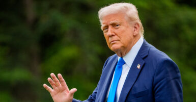 Donald Trump waves in a blue suit with a blue tie