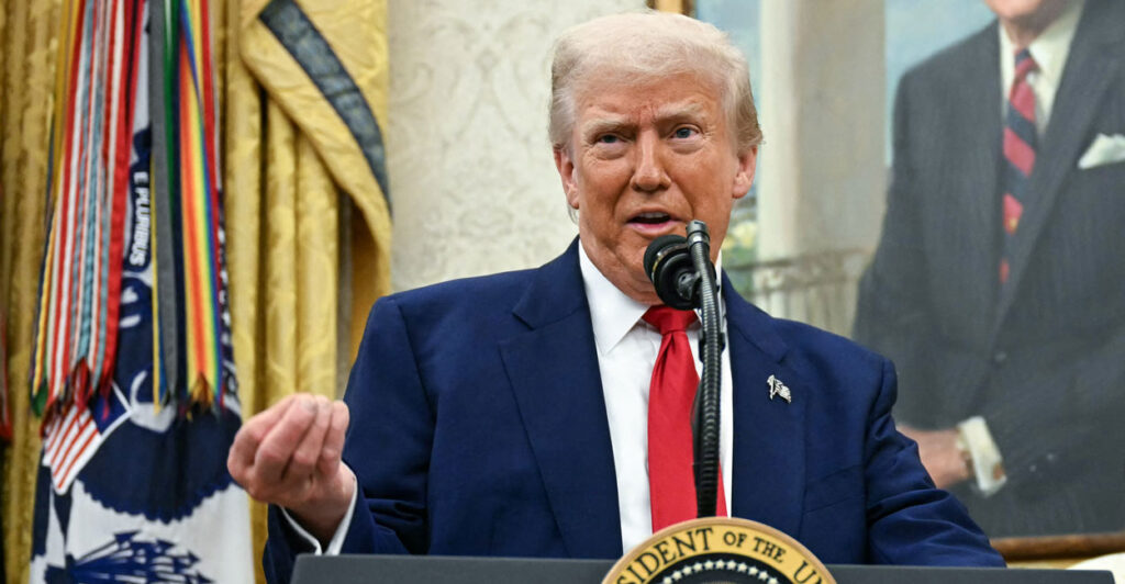 President Trump gestures while speaking behind a podium.
