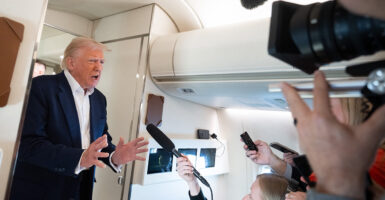 President Donald Trump speaks to reporters aboard Air Force One en route back to Washington from West Palm Beach, Fla., on Sunday.
