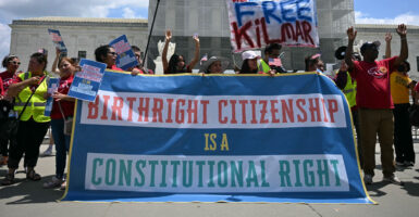 protesters outside the Supreme Court hold a large banner that says birthright citizenship is a constitutional right