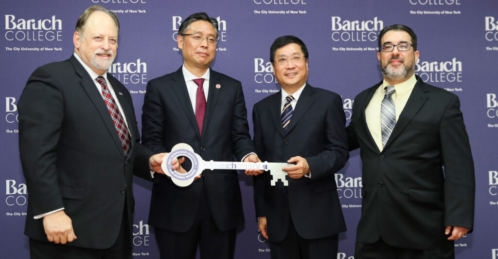 the president of Baruch College stands with three members of the Chinese Confucius Institutes, all holding a large ceremonial key and posing together for the camera