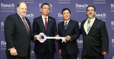 the president of Baruch College stands with three members of the Chinese Confucius Institutes, all holding a large ceremonial key and posing together for the camera