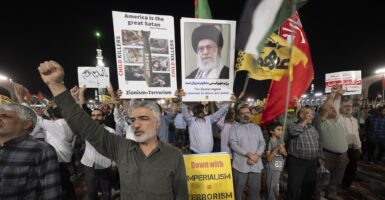 Iranian protesters shout anti-U.S. slogans while carrying a sign that says, "America is the great Satan."
