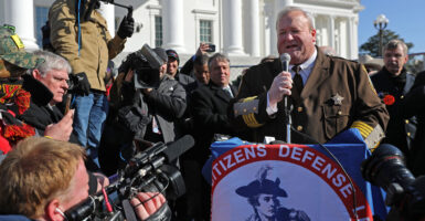 Culpeper County, Virginia, Sheriff Scott Jenkins in a brown uniform and surrounded by media speaks during a gun rights rally with the Virginia Capitol in the background