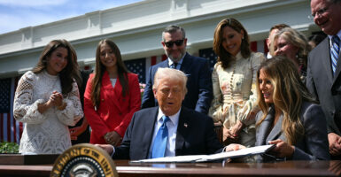 First lady Melania Trump (seated, right), Sen. Ted Cruz (standing, center), and others look on after President Donald Trump signed the Take It Down Act on Monday.