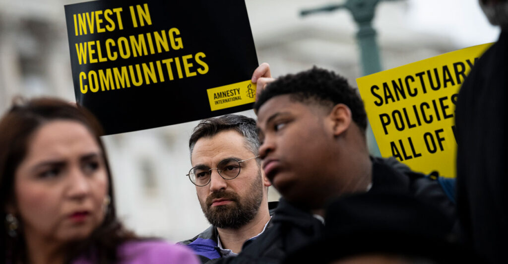 People hold signs saying “Invest in Welcoming Communities” during a press conference with congressional Democrats in support of sanctuary city mayors outside the U.S. Capitol.