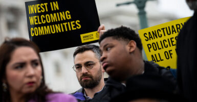 People hold signs saying “Invest in Welcoming Communities” during a press conference with congressional Democrats in support of sanctuary city mayors outside the U.S. Capitol.