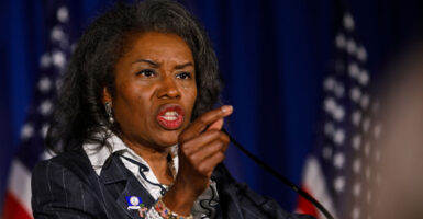 Virginia Lt. Gov. Winsome Earle-Sears speaks at a podium with American flags in the background and gestures by pointing her finger to the audience
