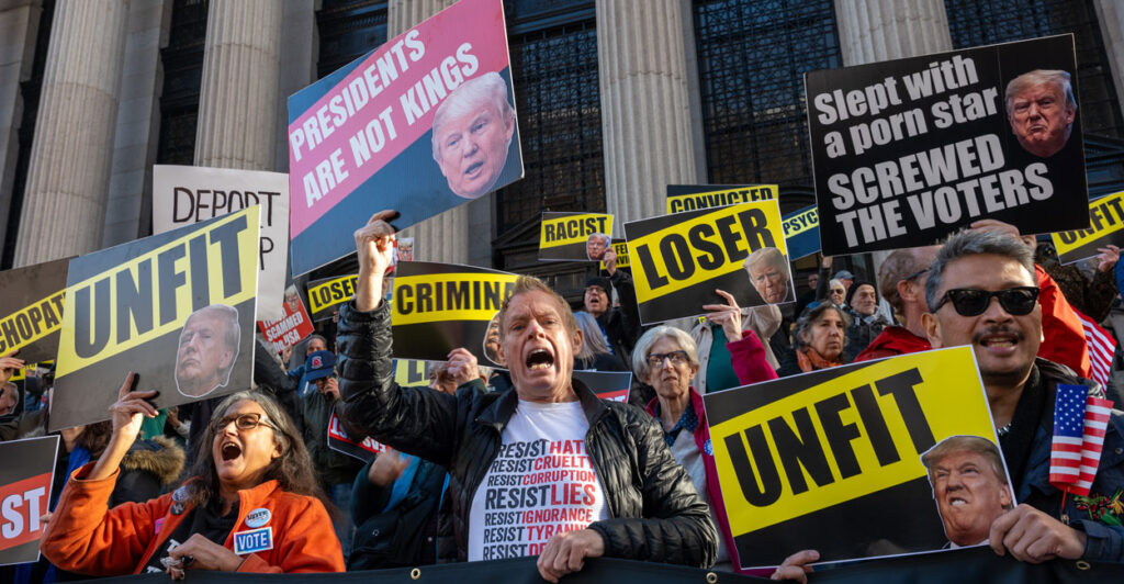 anti-Donald Trump protesters holding up signs such as unfit, loser, and criminal