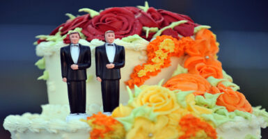 A colorful wedding cake for a same-sex marriage, with two male figurines in tuxes.