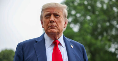 Donald Trump stops to talk to the media and looks to his right.