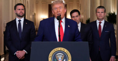 Donald Trump stands at podium with a microphone set in front of him as he gives a speech.